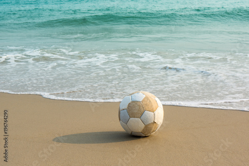 old football or soccer was lay on the beach with morning sunlight
