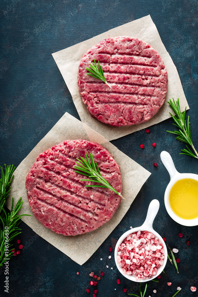 Fresh minced beef meat burgers with spices on dark background. Raw ground beef meat. Flat lay. Top view Fresh minced beef meat burgers with spices on dark background. Raw ground beef meat. Flat lay. Top view