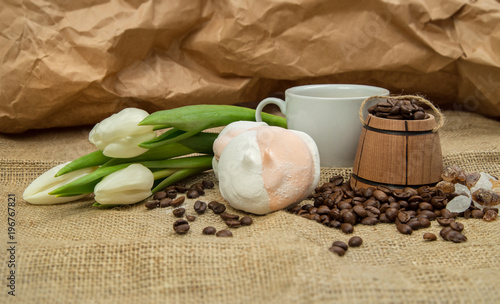 spring still-life from a cup of coffee with milk, marshmallow, a bouquet of white tulips on a rough background