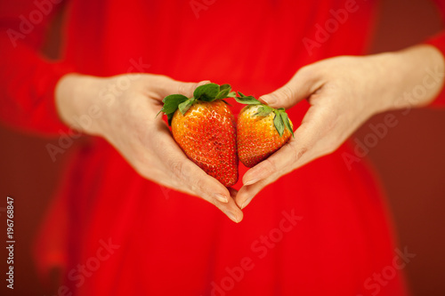Beautiful woman hands holding some strawberries in her hands, sensual studio shot can be used as background