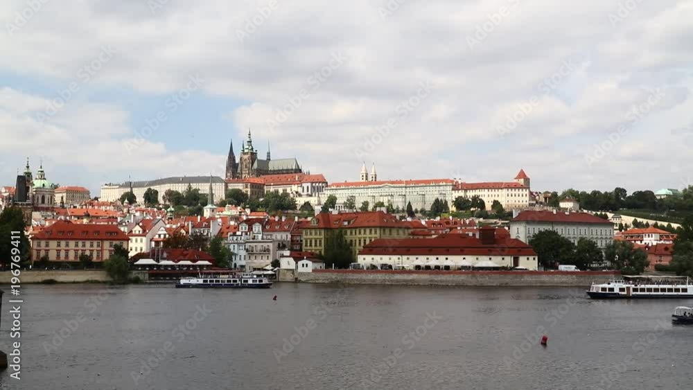 Day view of Prague lesser old town (Mala Strana) with Royal castle palace and Saint Vitus Cathedral over Vltava river under blue sky
