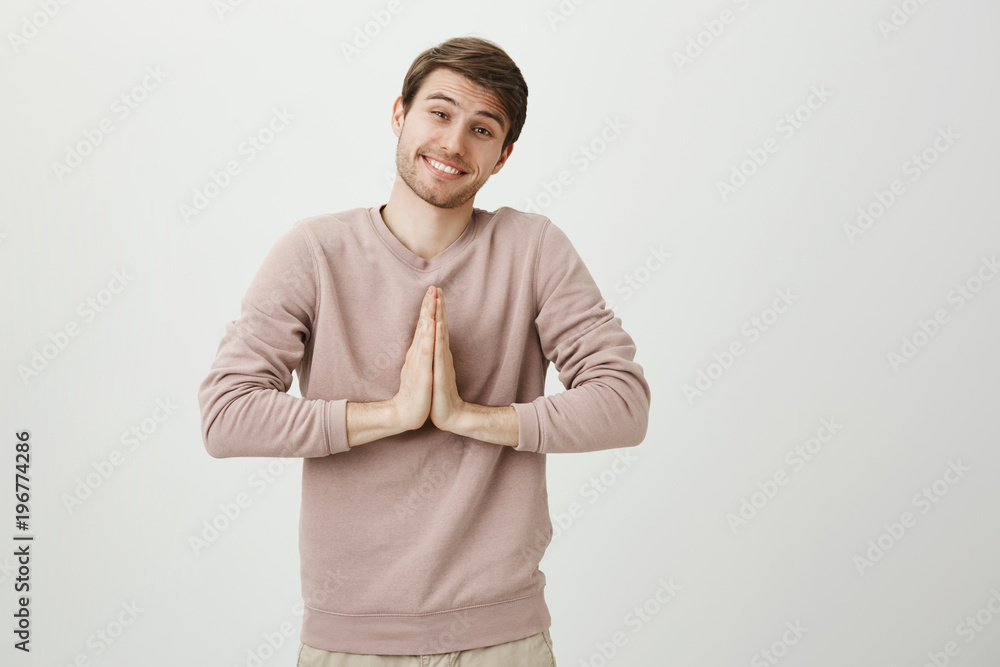 Charming boyfriend with bristle and cute eyes, smiling broadly while standing with praying or begging gesture and asking for favour, over gray background. Will you please go out with me tonight Charming boyfriend with bristle and cute eyes, smiling broadly while standing with praying or begging gesture and asking for favour, over gray background. Will you please go out with me tonight