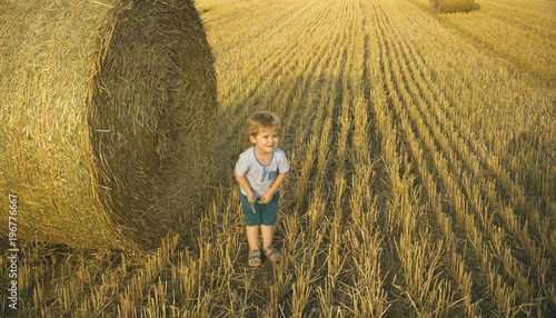Boy with wheat at haystack in field