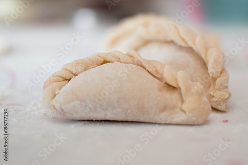 Homemade potstickers with flour laying on the modern cooking surface.