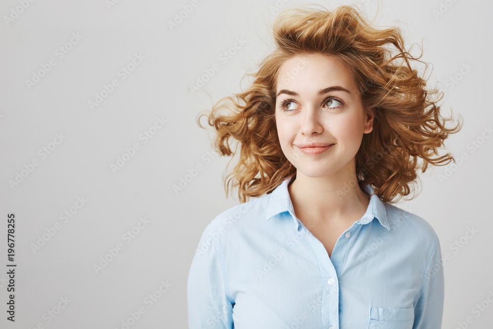 No wind can ruin my hairstyle. Charming confident european woman with short blonde curly hair looking aside and smiling sensually while standing in windy place or near fan over gray background No wind can ruin my hairstyle. Charming confident european woman with short blonde curly hair looking aside and smiling sensually while standing in windy place or near fan over gray background