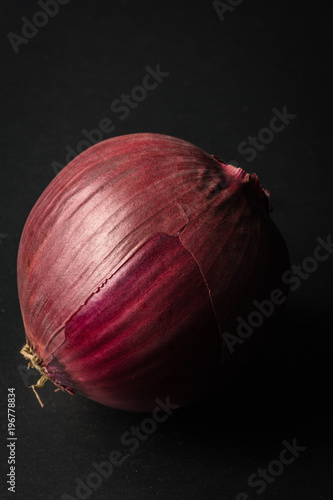 Foto Isolated and side lit red onion on a black background
