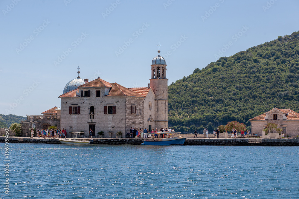Fjord in Adriatic Sea. Our Lady of the Rock island and Church in Perast on shore of Boka Kotor bay (Boka Kotorska), Montenegro, Europe.