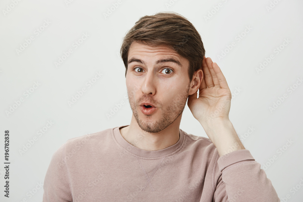 Guy enjoys put hit nose in business of other people. Thrilled handsome male holding palm near ear and saying wow, overhearing conversation and wanting to spread rumor, standing over gray wall Guy enjoys put hit nose in business of other people. Thrilled handsome male holding palm near ear and saying wow, overhearing conversation and wanting to spread rumor, standing over gray wall