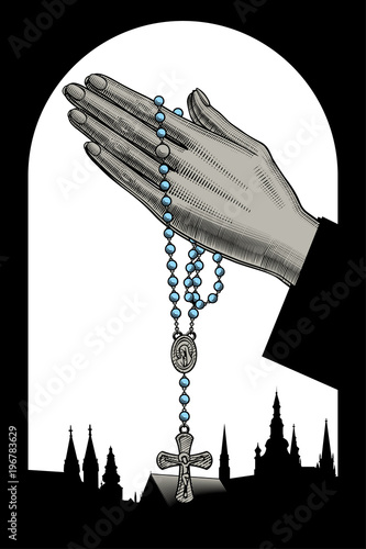 Woman's hands with prayer beads and silhouettes of catholic cathedrals. photo