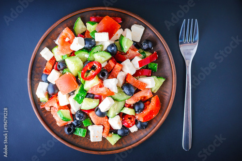 Greek salad in a plate on a dark background