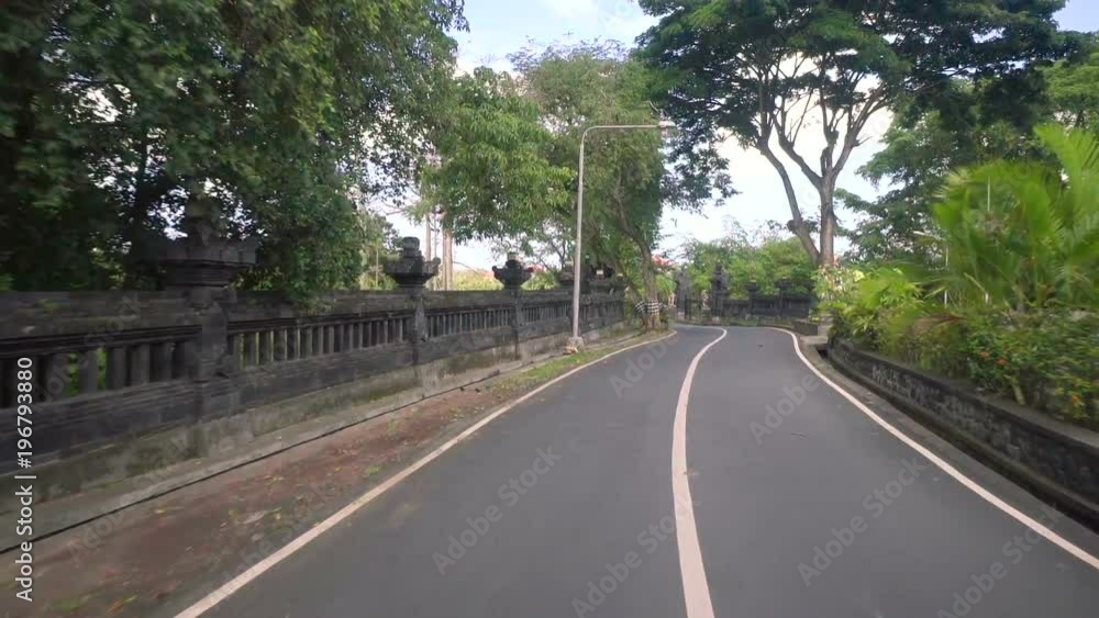 Moving on street with temples and walls in Bali Moving on street with temples and walls in Bali