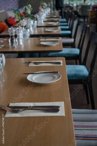 Glasses, flower fork, knife served for dinner in restaurant with cozy interior