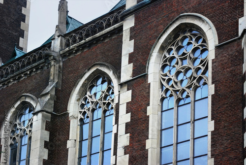 Catholic church. Baroque and Gothic architecture. Vaulted window with stained glass on facade of the building.