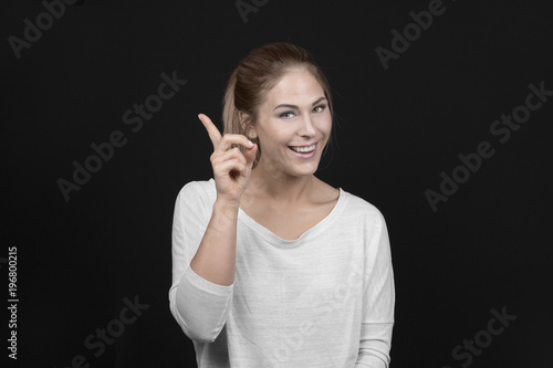 Excited blond hair young woman pointing - have an idea, on black Background