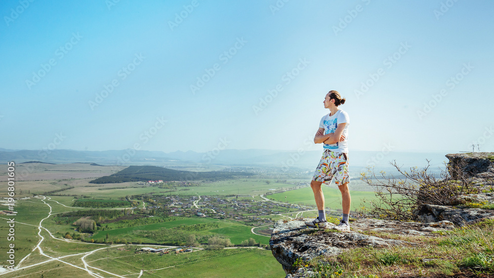Naklejka premium Photo of young handsome serious man standing over mountains and looking aside
