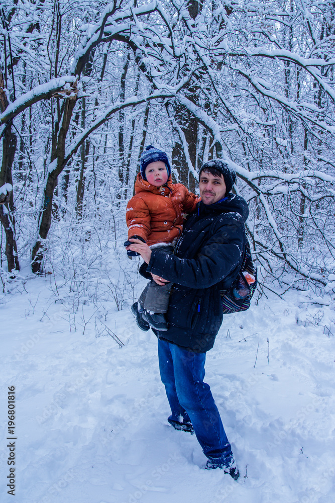 Father and his son playing outside, winter forest on the background, snowing, happy and joyful Father and his son playing outside, winter forest on the background, snowing, happy and joyful