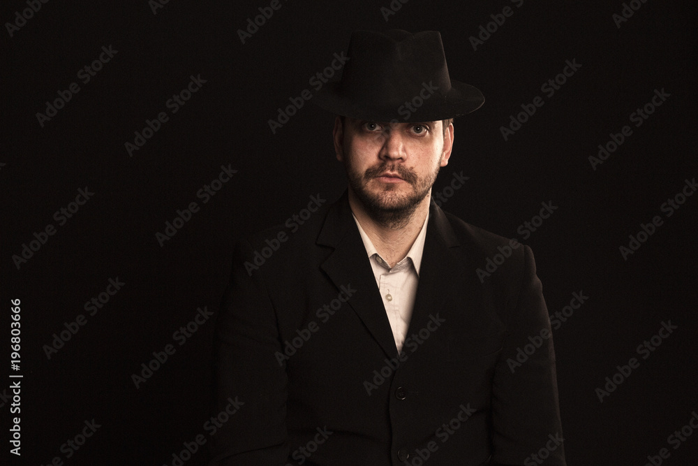 man in a classic suit and hat on a black background looks at the frame man in a classic suit and hat on a black background looks at the frame