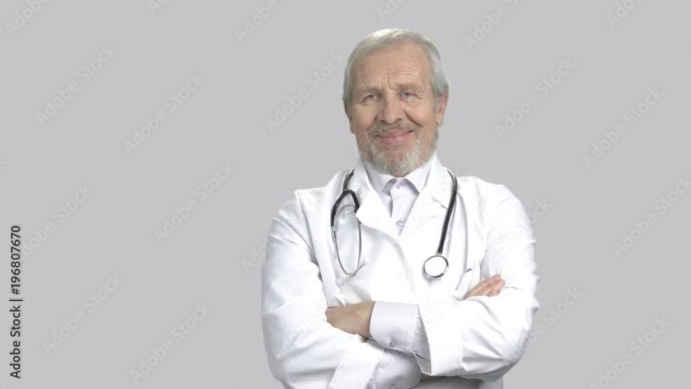 Senior male doctor with stethoscope. Elderly cardiologist crossed arms on grey background, portrait. Senior male doctor with stethoscope. Elderly cardiologist crossed arms on grey background, portrait.