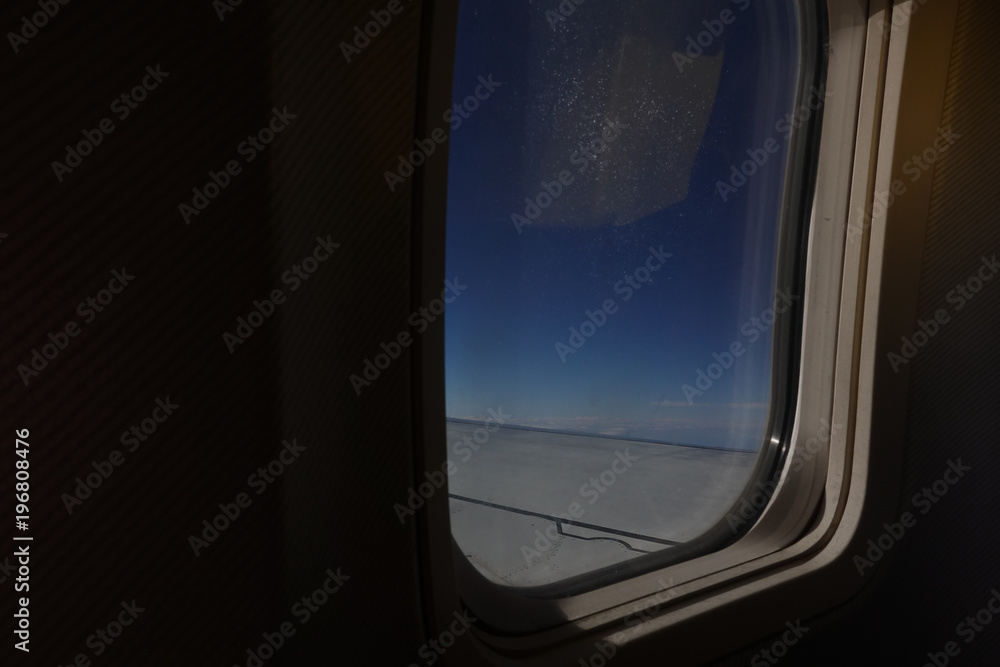 Aicraft window and sky from inside cabin economy class