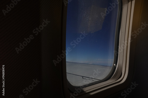 Aicraft window and sky from inside cabin economy class