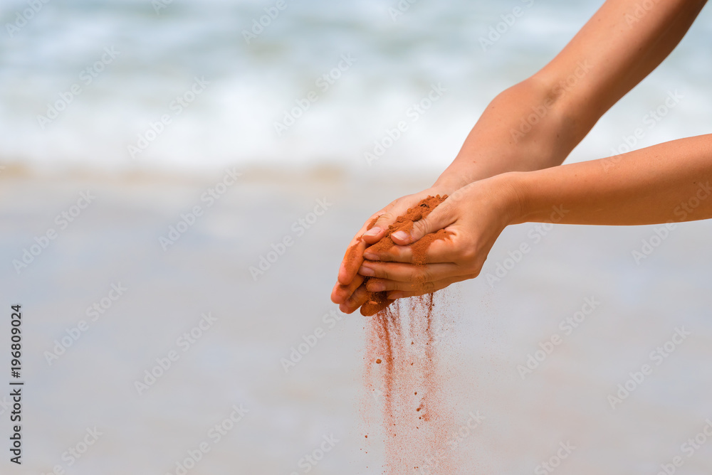 Woman hands holding red sand on the beach in aboriginal art style