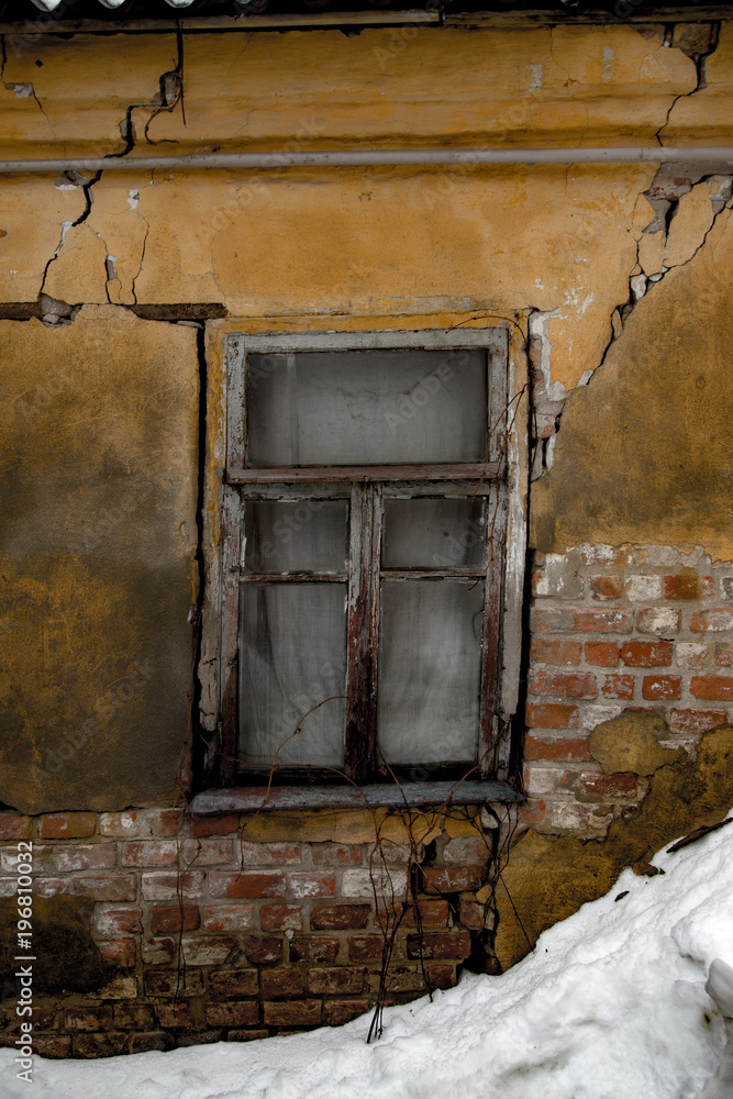 Shabby grungy cracked wall, broken windows, abandoned house, winter, poverty concept Shabby grungy cracked wall, broken windows, abandoned house, winter, poverty concept