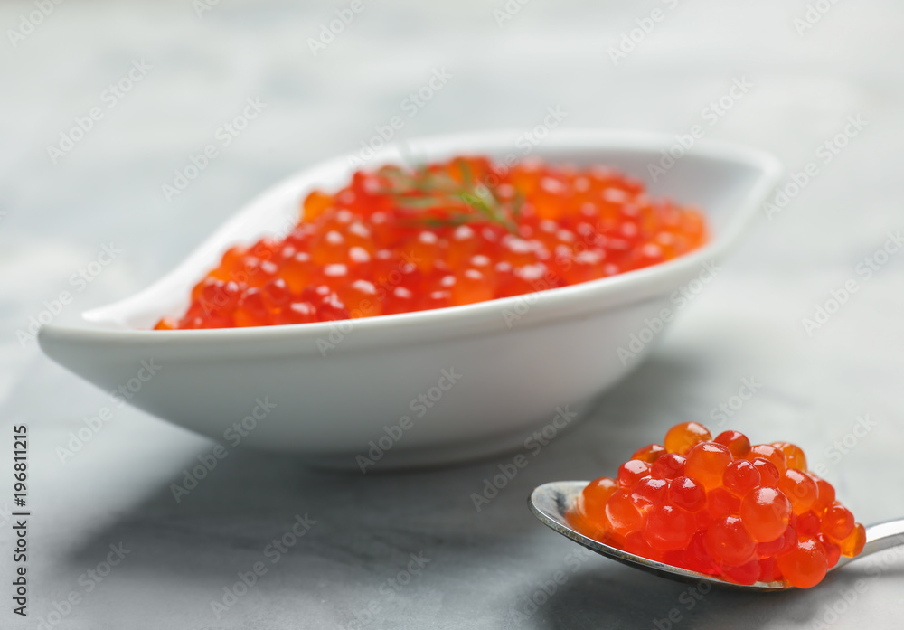 Bowl and spoon with delicious red caviar on table Bowl and spoon with delicious red caviar on table