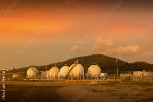 Spherical  storage tank storing liquefied gas and chemical liquids on sunset sky.