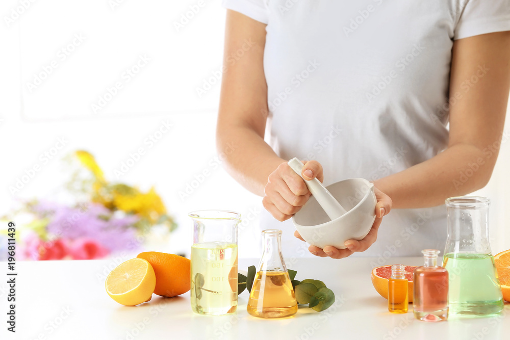 Woman preparing perfume oil at table indoors Woman preparing perfume oil at table indoors