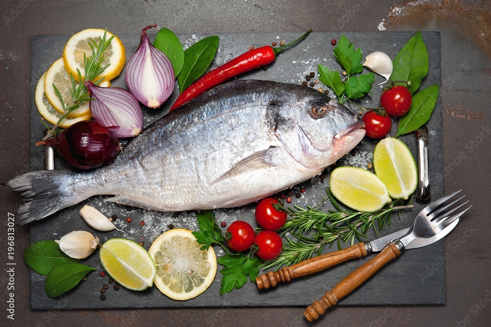 raw fish Dorado with spices and vegetables on slate plate raw fish Dorado with spices and vegetables on slate plate