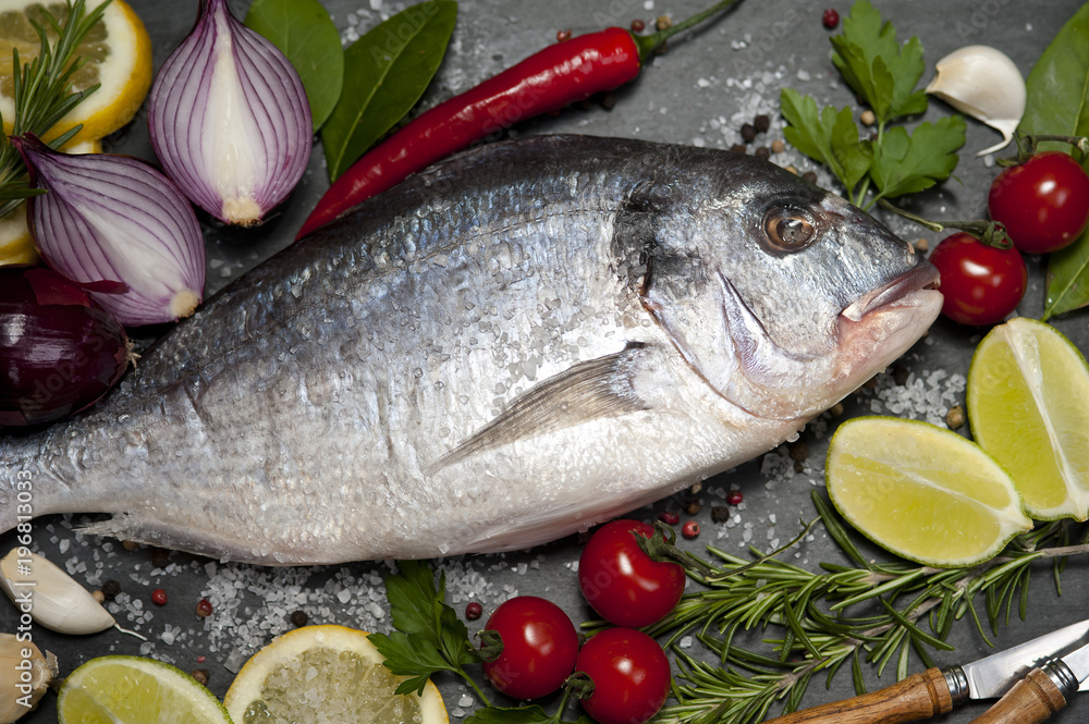 Fresh Dorado fish with spices and vegetables on slate plate Fresh Dorado fish with spices and vegetables on slate plate