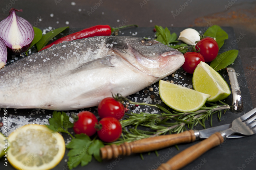 raw fish Dorado with spices and vegetables on slate plate raw fish Dorado with spices and vegetables on slate plate