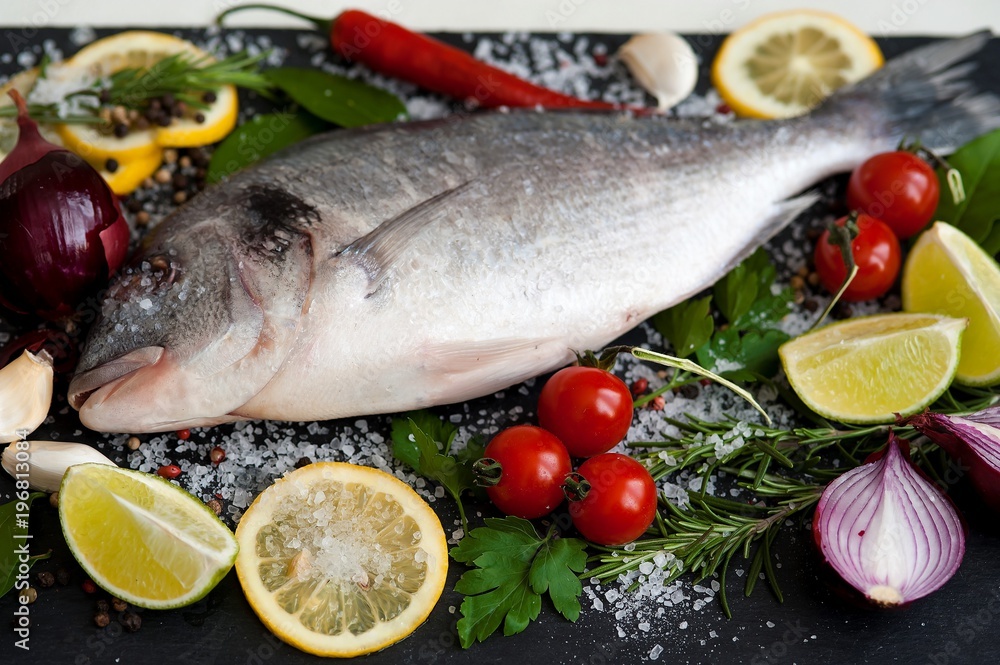Fresh Dorado fish with spices and vegetables on slate plate Fresh Dorado fish with spices and vegetables on slate plate