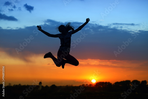 Cheerful athletic girl practicing for the beautiful red sunset background.