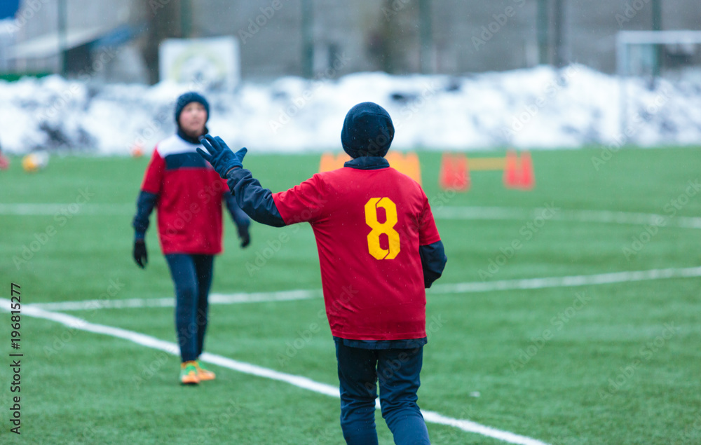 boys play football on the winter stadium