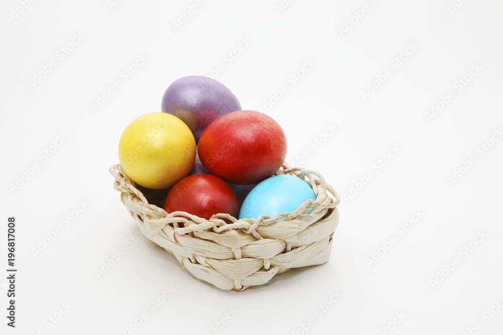 Naklejka premium Basket full of Easter eggs on white background with copy space for text.