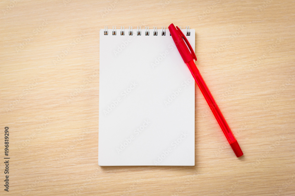 Red pen with notebook on wooden table Red pen with notebook on wooden table