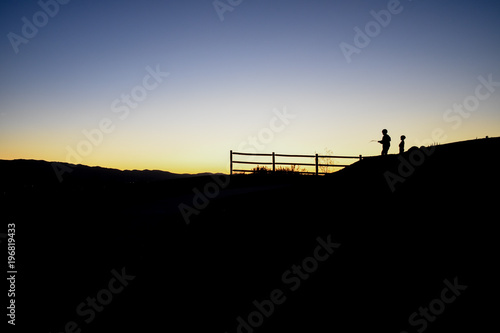 Sunset sky with twilight hues showing foreground silhouettes of fence railing.