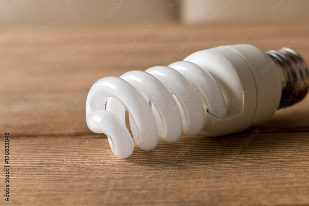 Energy-saving light bulb lies on a wooden table Energy-saving light bulb lies on a wooden table