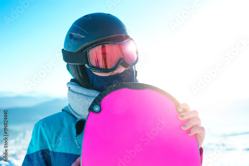 Young woman skier with snowboard in helmet and ski mask outdoors