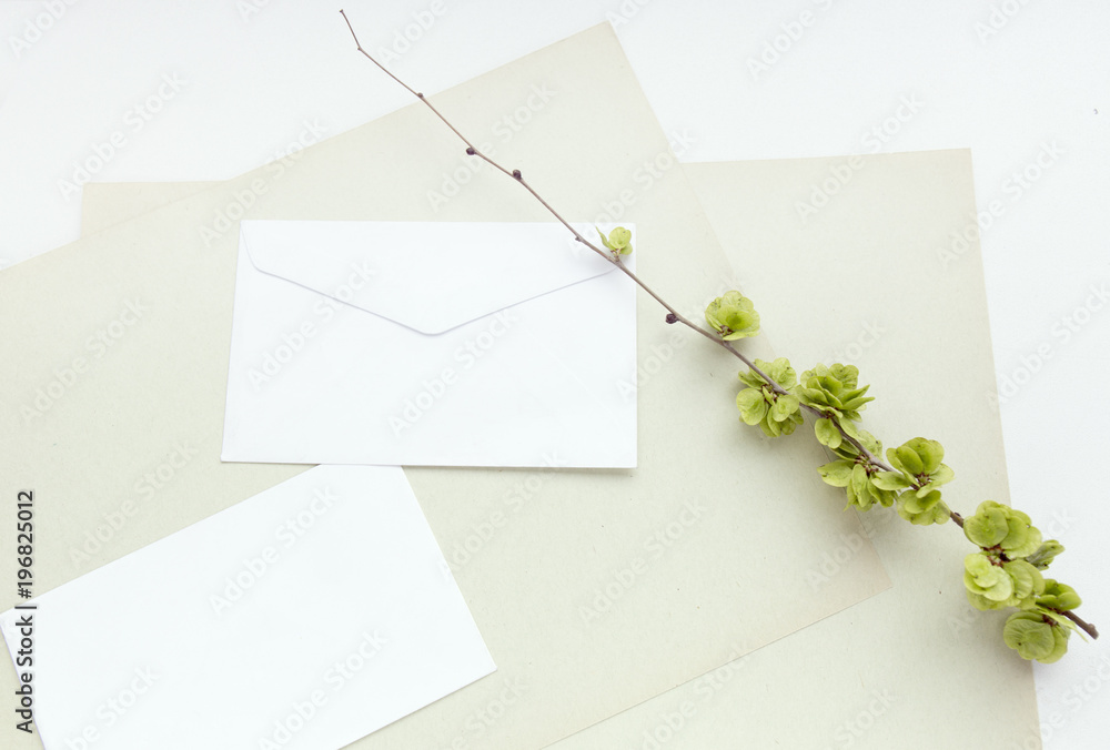 Craft paper sheets and white envelope. Blank card and spring green leaves. Mockup design. Top view with copy space. Craft paper sheets and white envelope. Blank card and spring green leaves. Mockup design. Top view with copy space.