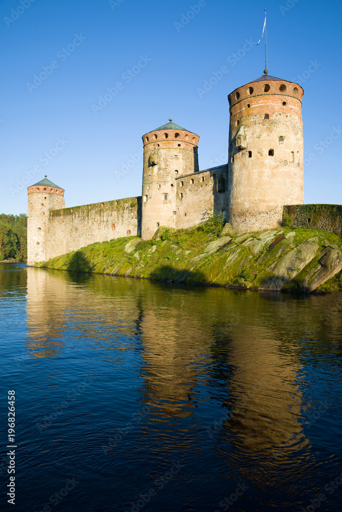 Towers of the Olavinlinna fortress in the rays of the setting sun in the August evening. Savonlinna, Finland
