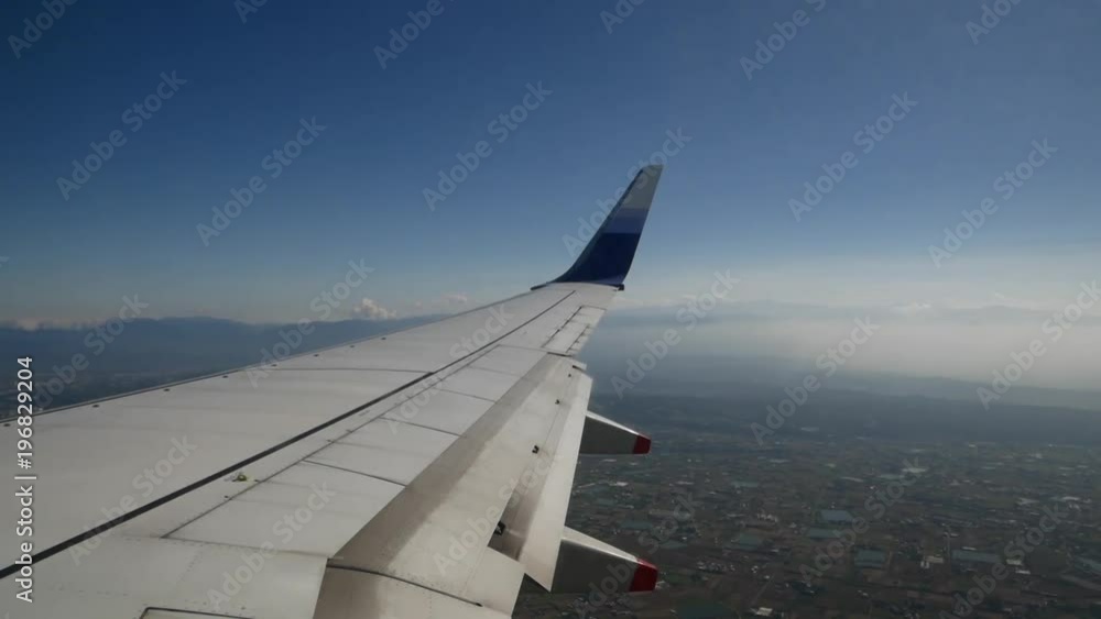 Day shot of airplane flying over Taipei City, view from wing, mountains and clouds can be seen in the back Day shot of airplane flying over Taipei City, view from wing, mountains and clouds can be seen in the back