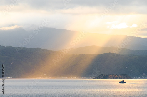 Stunning landscape sunrise in the morning. Golden light go through the cloud to the mountain and sea.