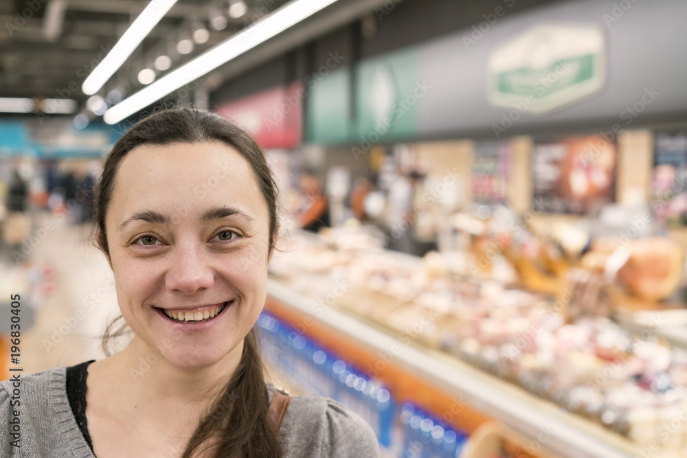 A cheerful middle-aged woman with long hair in a supermarket.