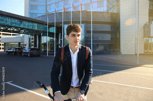 Confident young businessman walking with bicycle on the street in town. photo