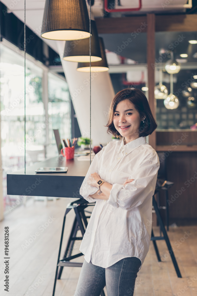 Beautiful business woman standing cross one's arm and smiling in coworking spaces. Beautiful business woman standing cross one's arm and smiling in coworking spaces.