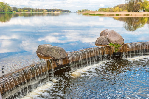 Landscape with waterfall on dam on beautiful lake