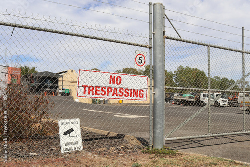 a No Trespassing and Surveillance Cameras In Use signs near the entrance of a business in an industrial area