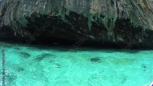 Yacht going around rock hill in sea water, beautiful turquoise lagoon, white sand 
